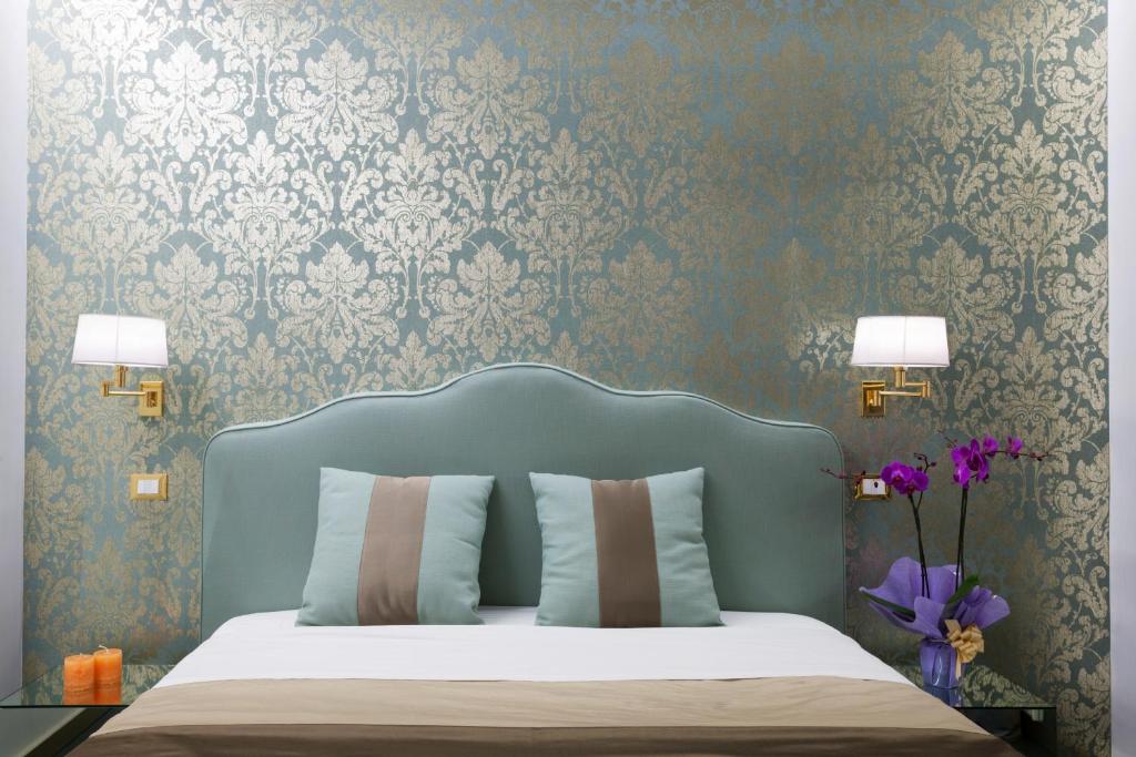 a bedroom with a bed with a blue headboard and wallpaper at Residenza Monfy in Rome