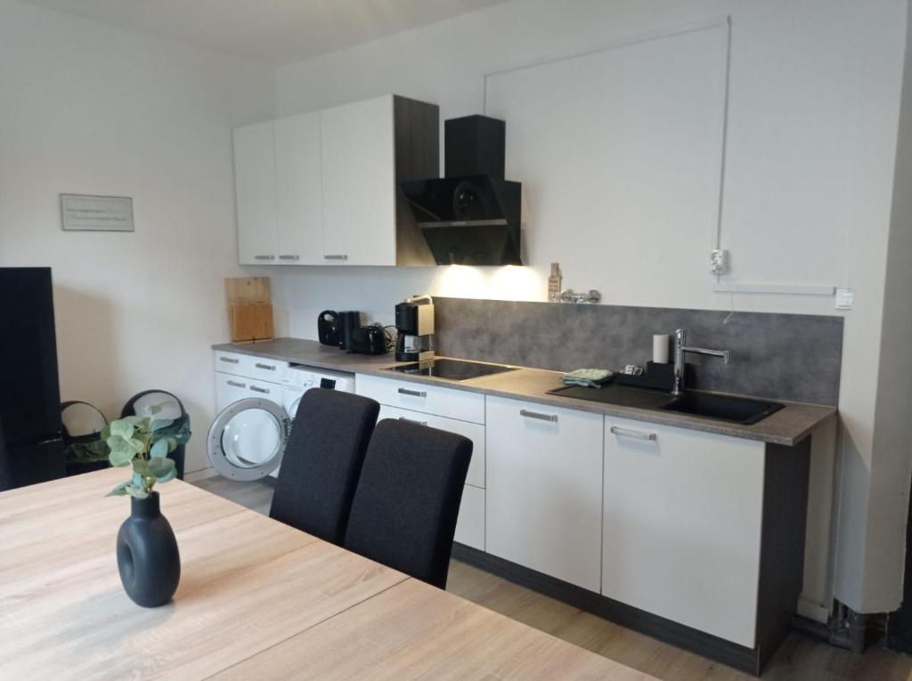 a kitchen with white cabinets and a table with chairs at Work and Stay 6 Zimmer 150qm 12 Betten 3 Badezimmer in Meinerzhagen