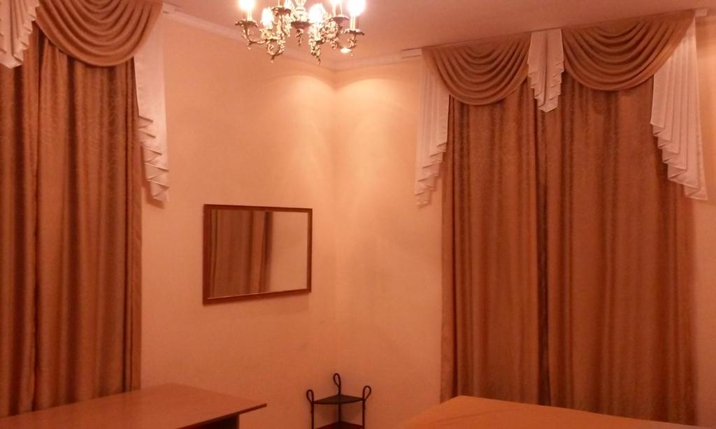 リヴィウにあるArmenian Kvartalの茶色のカーテンとシャンデリアが備わるお部屋