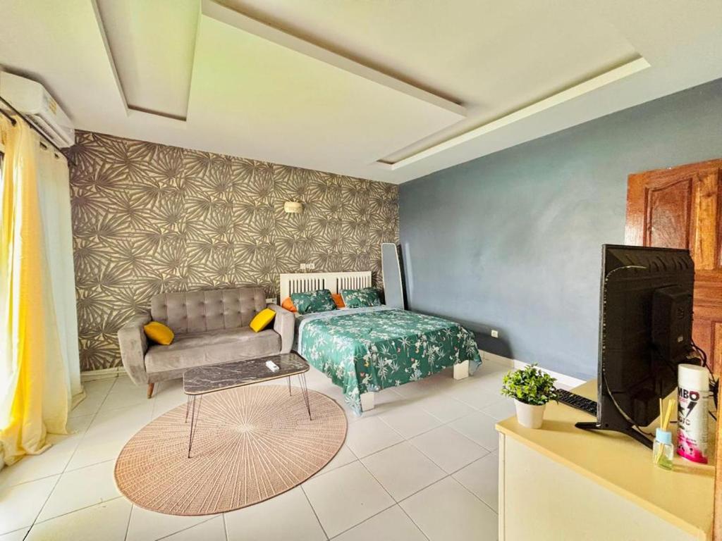Un dormitorio con una cama, un sofá y un televisor. en Laetitia Belle Vue, en Abiyán
