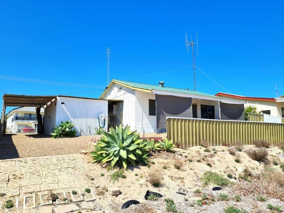 une maison dans le désert avec une clôture et une cour dans l'établissement Crab Claw Cottage, à Port Broughton