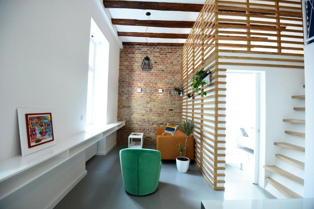 Habitación con silla verde y pared de ladrillo en Leo & Coco Apartments, en Zagreb