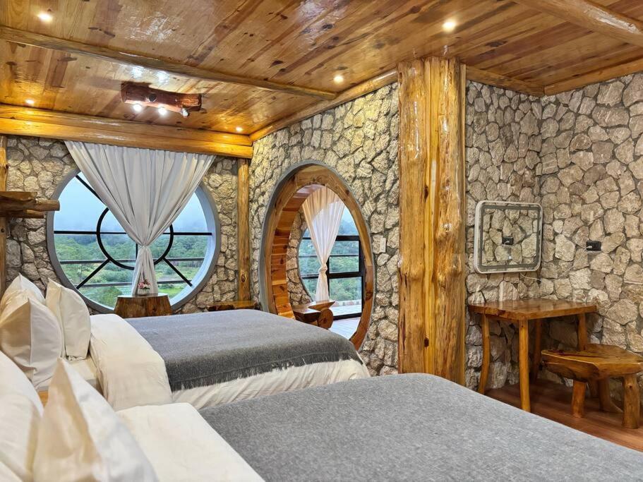a bedroom with two beds and a stone wall at Bugnay Cabin of The Shire in Sagada