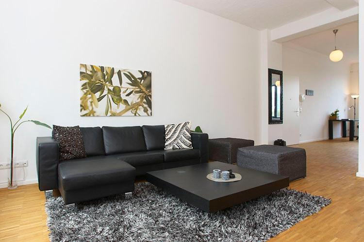 a living room with a black couch and a coffee table at Spacious Studio Apartment Friedrichshain in Berlin
