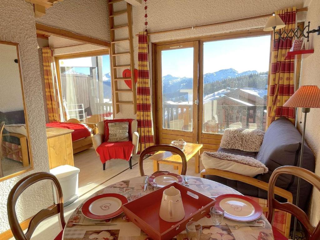 - un salon avec une table, des chaises et une grande fenêtre dans l'établissement Studio familial 4 pers avec balcon, casier skis, animaux admis - FR-1-594-332, à Hauteluce