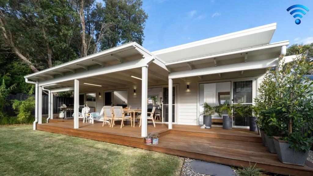 ein Haus mit einer Holzterrasse in der Unterkunft Sunshine Cottage in Culburra Beach