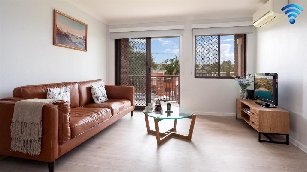 a living room with a brown leather couch and a television at Miami Kiama in Kiama
