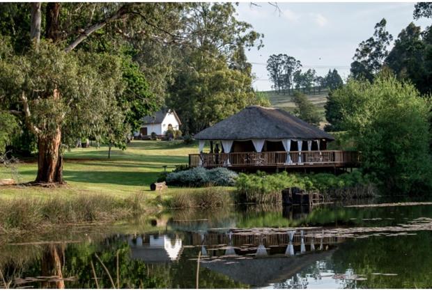 a gazebo with a roof next to a lake at The Retreat Country Lodge in Romelcoh