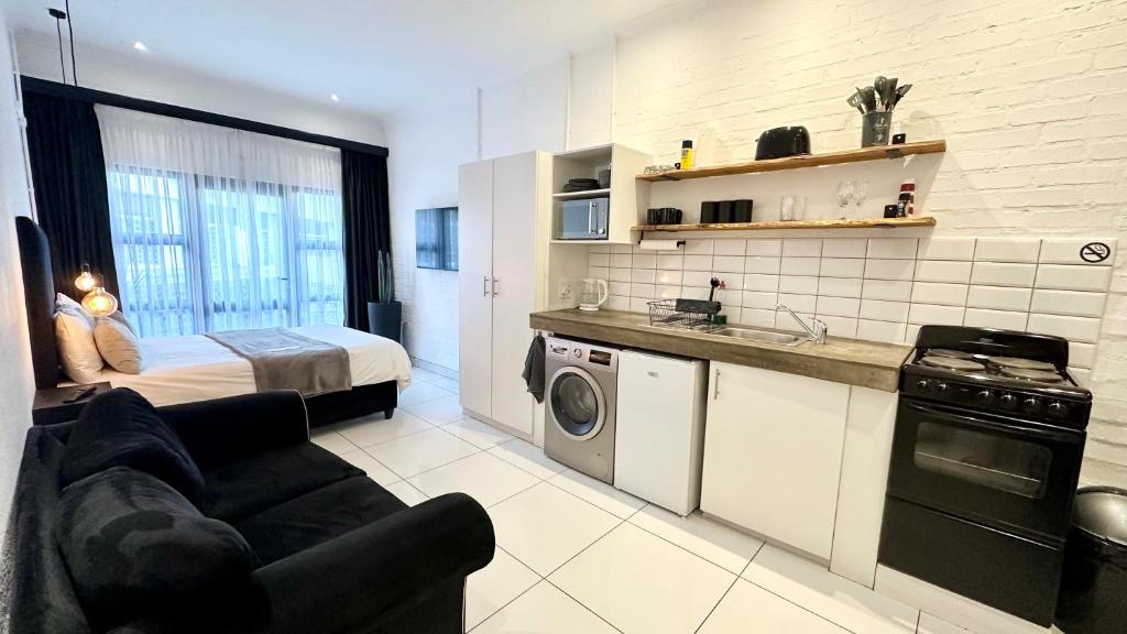 a living room with a bed and a kitchen with a couch at Industrial CHIC Apartment 113 - Luxury City Escape, Washing Machine & Fast WiFi in Johannesburg
