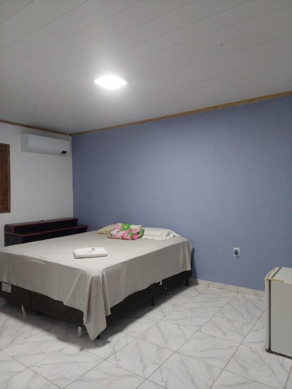 a bedroom with a bed in a blue wall at Qroom Janaina in Cruzeiro do Sul