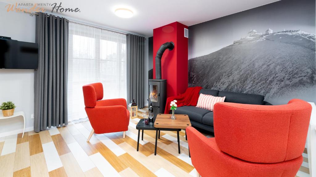 a living room with red chairs and a couch at Wonder Home - Domki górskie z kominkami, bezpłatnym parkingiem i placem zabaw na terenie kompleksu in Karpacz