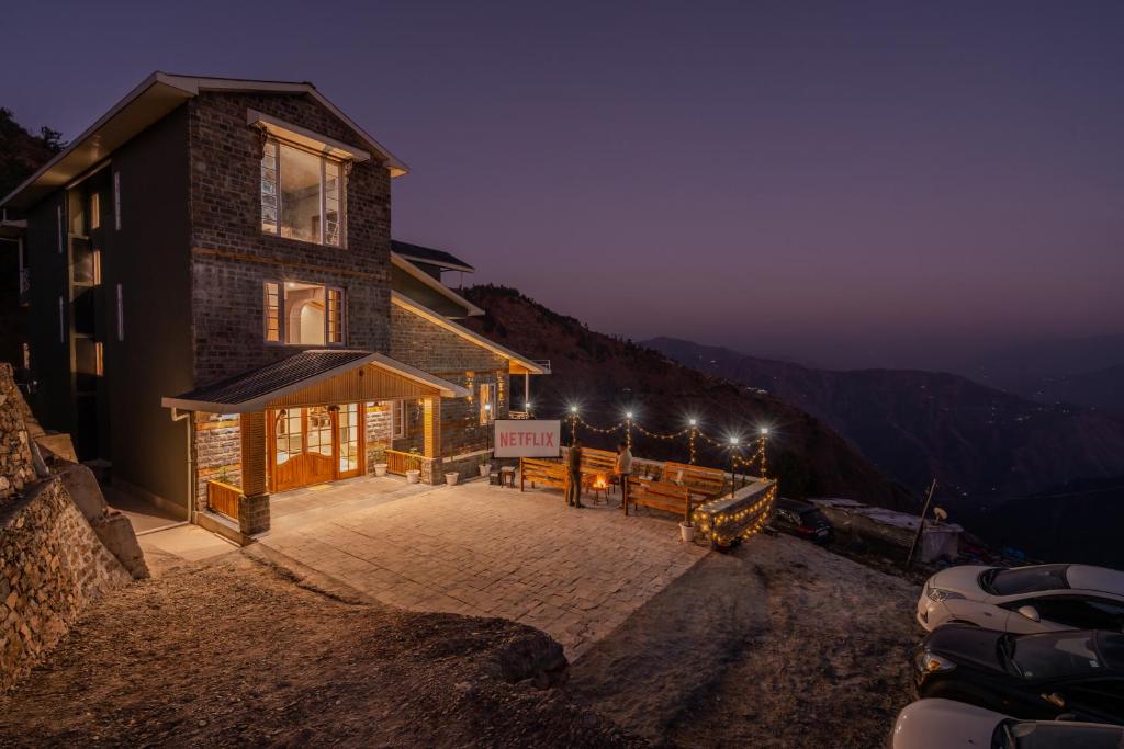 a building on the side of a mountain at night at SaffronStays Alpine Blue, Theog - 6BR Villa with Valley Views in Shimla