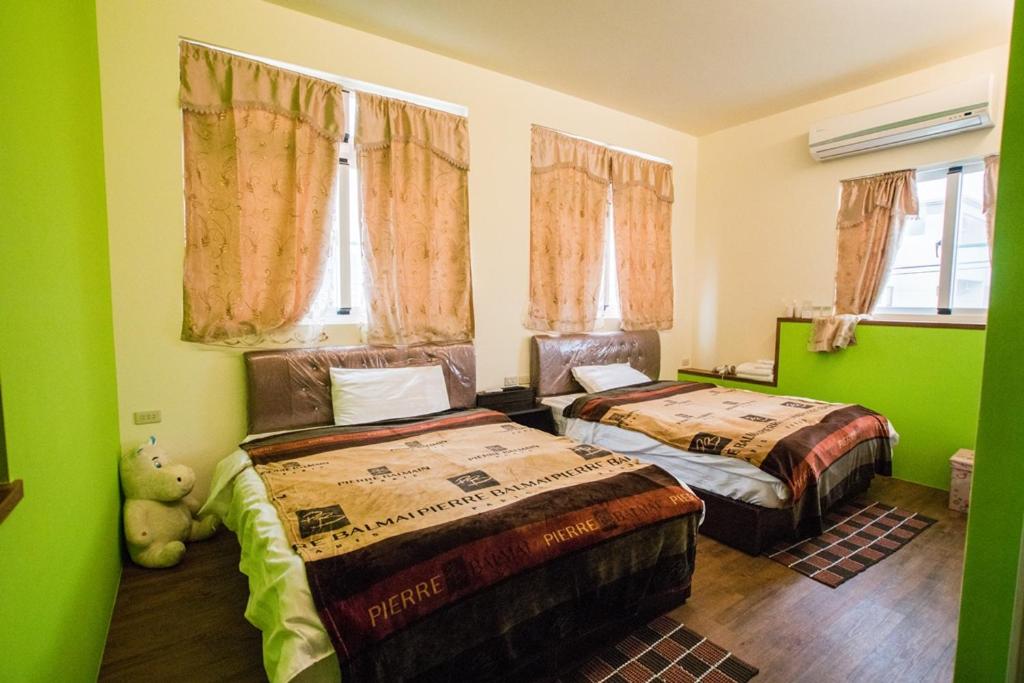 台東市的住宿－小燕子民宿，配有两张床铺的绿色墙壁和窗户
