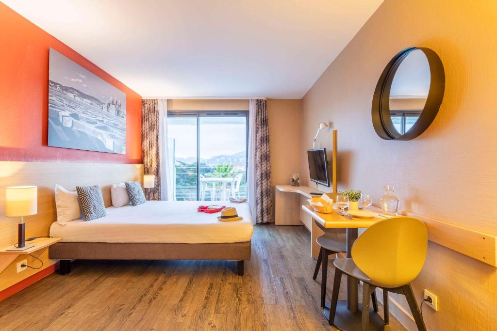 a hotel room with a bed and a table and a desk at Comfort Aparthotel Marseille Prado in Marseille