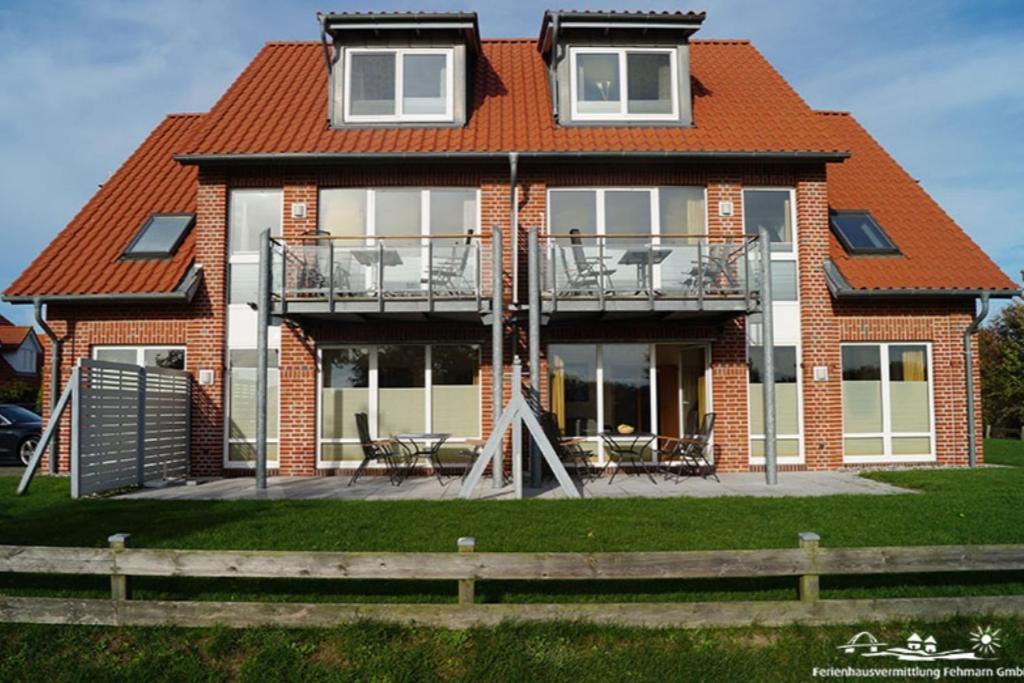 a brick house with a deck and a balcony at 53 Ferienwohnung im Fritz-Bleyl-Weg 14 OG rechts in Burg auf Fehmarn