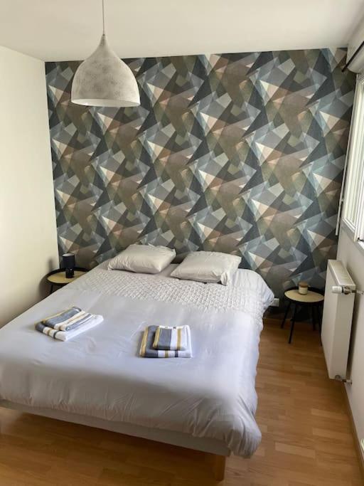 - une chambre avec un lit blanc et un mur géométrique dans l'établissement Bel appartement proche gare - WiFi - parking, à Vesoul