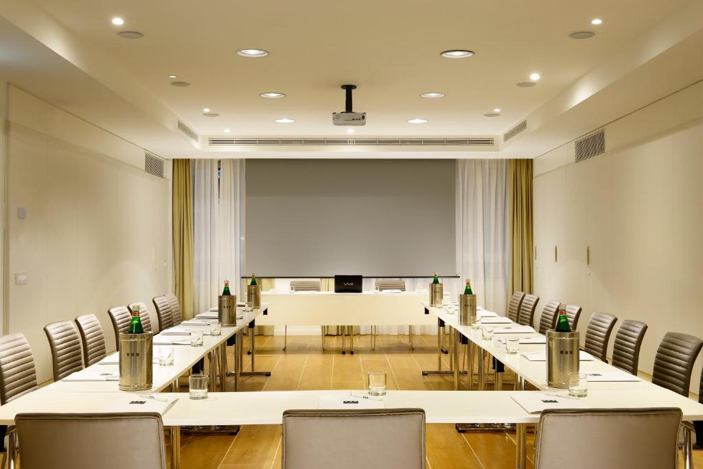 sala konferencyjna ze stołami i krzesłami oraz ekranem projekcyjnym w obiekcie UNA HOTELS Century Milano w Mediolanie