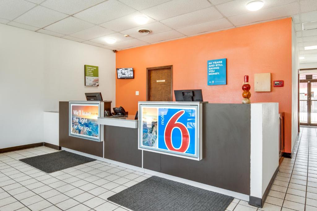 a cashier counter in a waiting room with an orange wall at Motel 6-Longview, TX - North in Longview