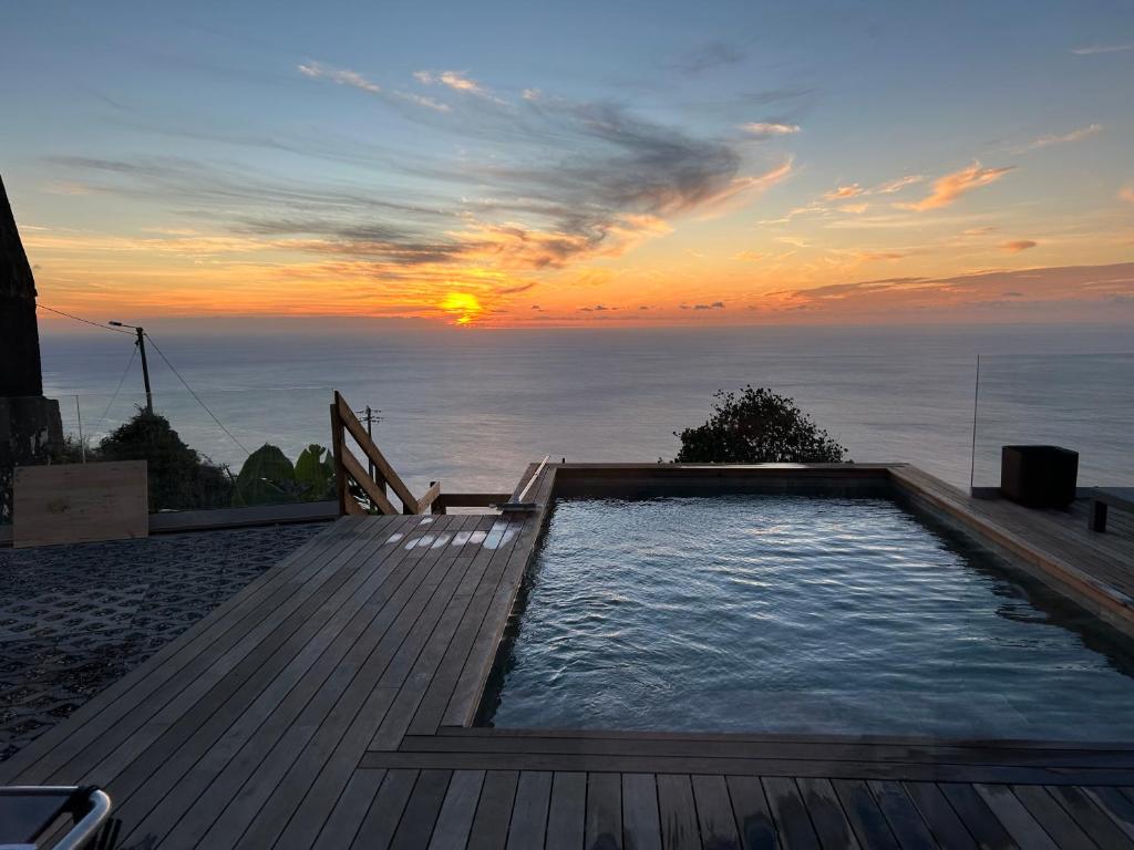 Una piscina con una puesta de sol al fondo en Villa MARIE, en Fajã da Ovelha