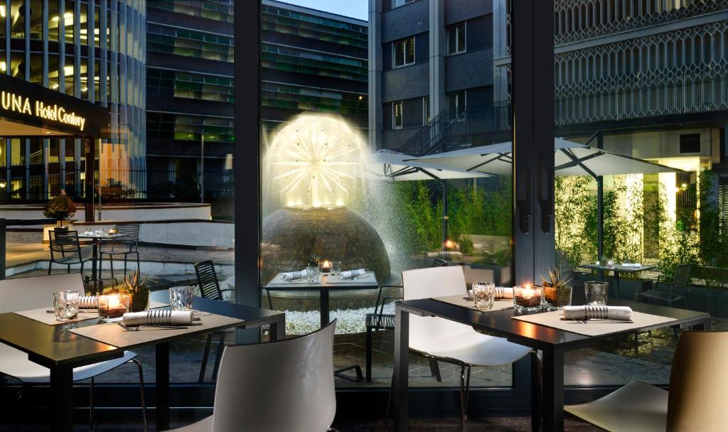 restauracja ze stołami i krzesłami oraz fontanną w obiekcie UNA HOTELS Century Milano w Mediolanie