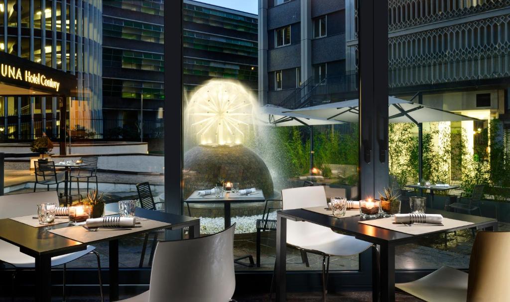 a restaurant with tables and chairs and a fountain at UNAHOTELS Century Milano in Milan