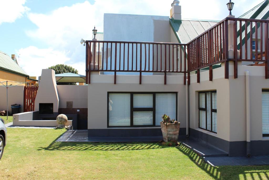 a house with a balcony on top of it at Holiday Villa Diaz Beach Mossel Bay in Mossel Bay