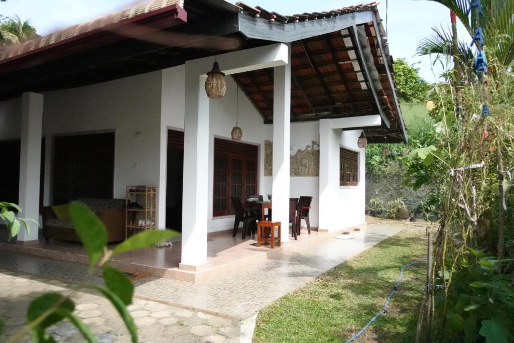 une maison avec une terrasse couverte et une salle à manger dans l'établissement Coco Mango Hostel, à Dikwella
