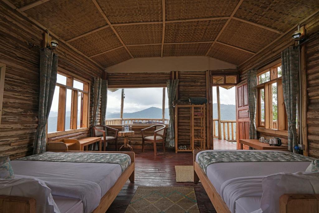 a bedroom with two beds and a table and chairs at Orugano Bwindi Lodge in Kisoro