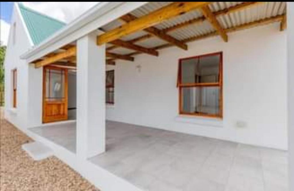 a white house with a porch and windows at De Rust Karoo Cottages in De Rust