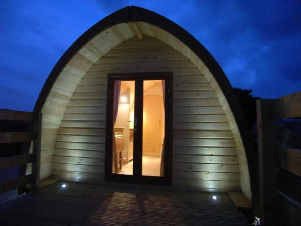 une petite maison avec une porte voûtée la nuit dans l'établissement Cabane 3 étoiles - Piscine - eececg, à Chamberet