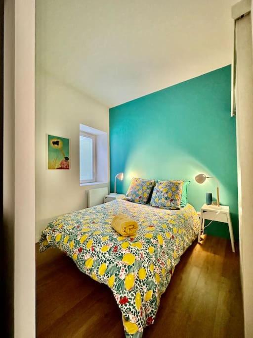 une chambre avec un lit avec un mur bleu dans l'établissement Le petit Musée À 2 pas des Arènes, à Nîmes