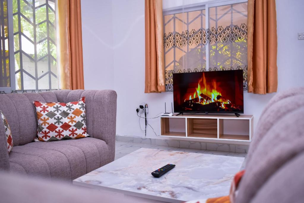 a living room with a couch and a tv at Villa's - Beach 2 km, Wifi, SmartTV, Parking - by Mango Tree Cottages Kilifi in Kilifi