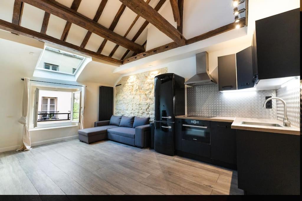 - une cuisine équipée d'appareils noirs et un canapé dans la chambre dans l'établissement Appartement Place des Vosges, Marais Bastille, à Paris
