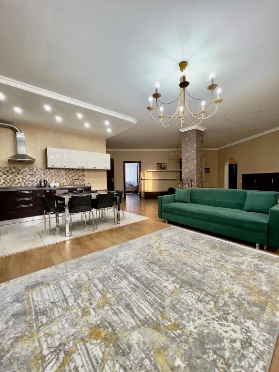ein Wohnzimmer mit einer grünen Couch und einem Tisch in der Unterkunft 205 Очень теплая 3 комн квартира у Байтерека с 3 большими кроватями и раскладным диваном для 1-8 человек in Astana