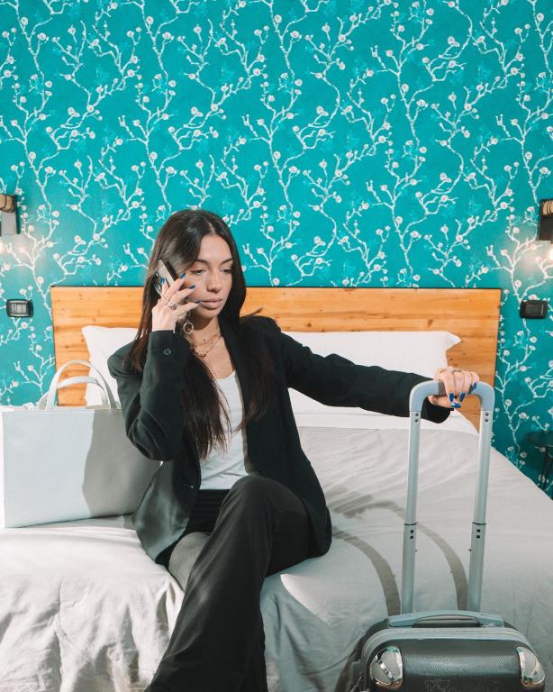 a woman sitting on a bed talking on a cell phone at TRAVEL STATION Bedandbreakfast in Bari