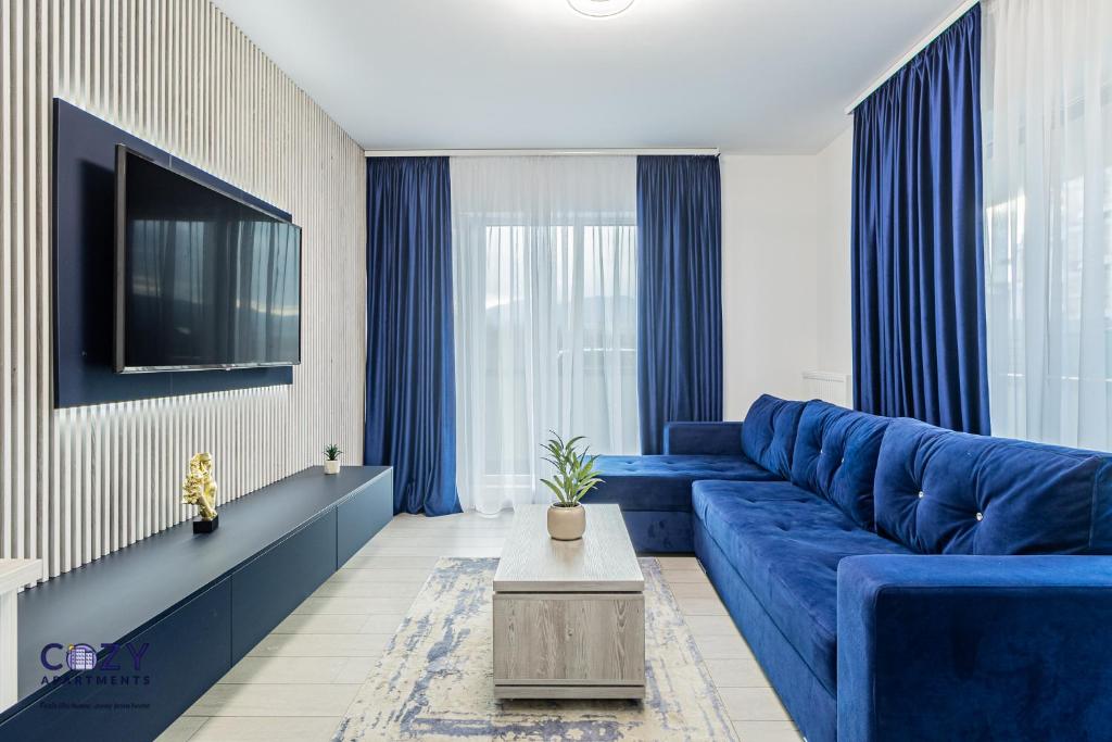 a living room with a blue couch and a tv at Luxury Residences & Suites in Central Brasov at Coresi Mall in Braşov