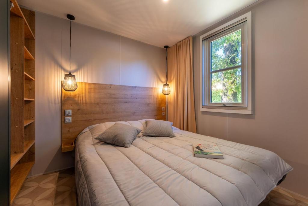 une chambre avec un grand lit et une fenêtre dans l'établissement CAMPING LES OURMES, à Hourtin 37 autres photos