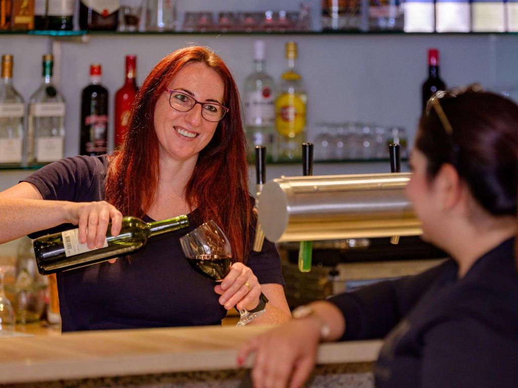 a woman pouring a glass of wine at a bar at ibis Stuttgart Airport Messe in Leinfelden-Echterdingen