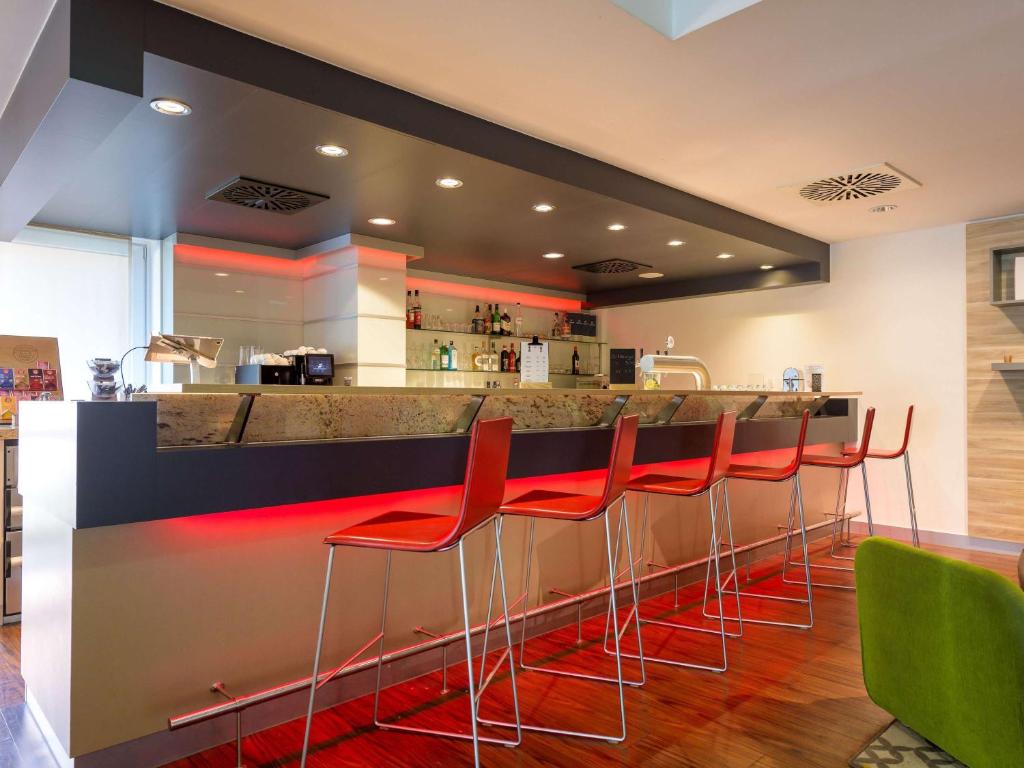 a bar with red bar stools in a restaurant at ibis Stuttgart Airport Messe in Leinfelden-Echterdingen