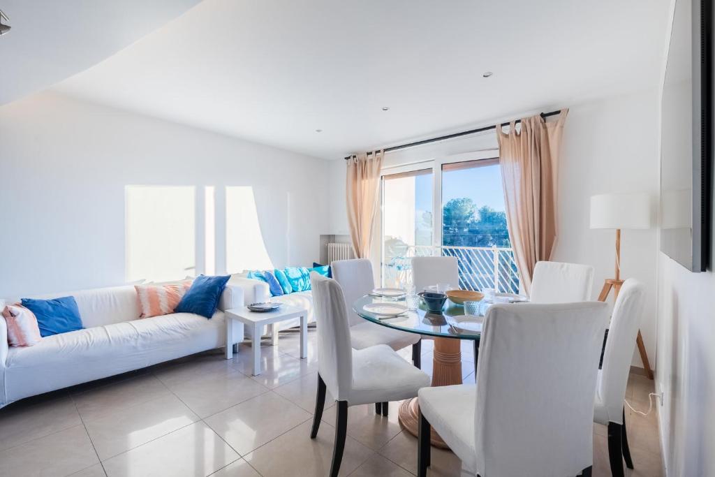 un salon avec une table et des chaises blanches dans l'établissement Appartement Éclat Marin - Welkeys, à Bandol