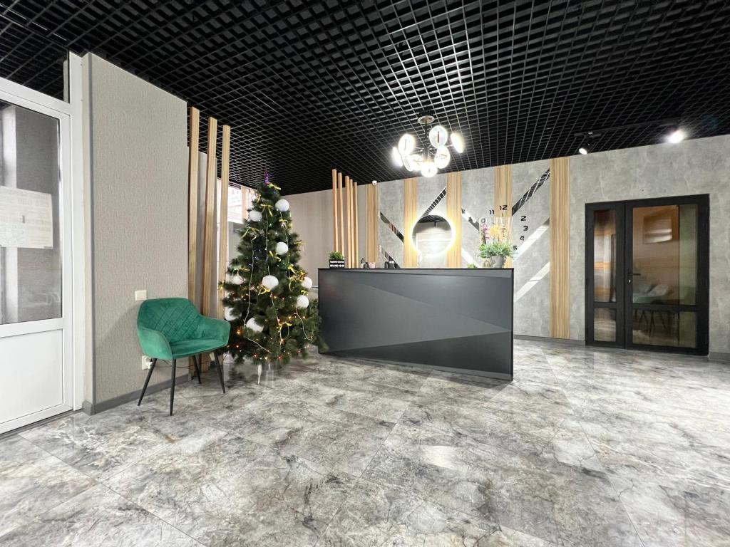 a christmas tree in a lobby with a green chair at Готельно-ресторанний комплекс Поділля in Bershadʼ