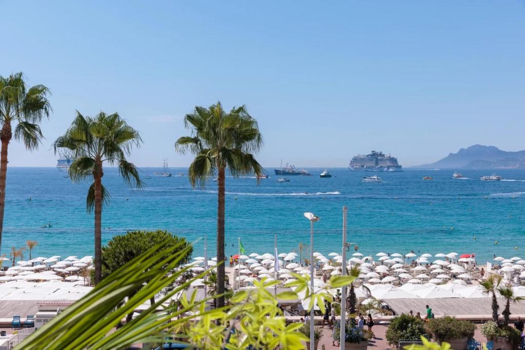 - une plage avec des palmiers et l'océan avec des parasols dans l'établissement 1973 - Luxurious waterfront apartment Croisette, à Cannes