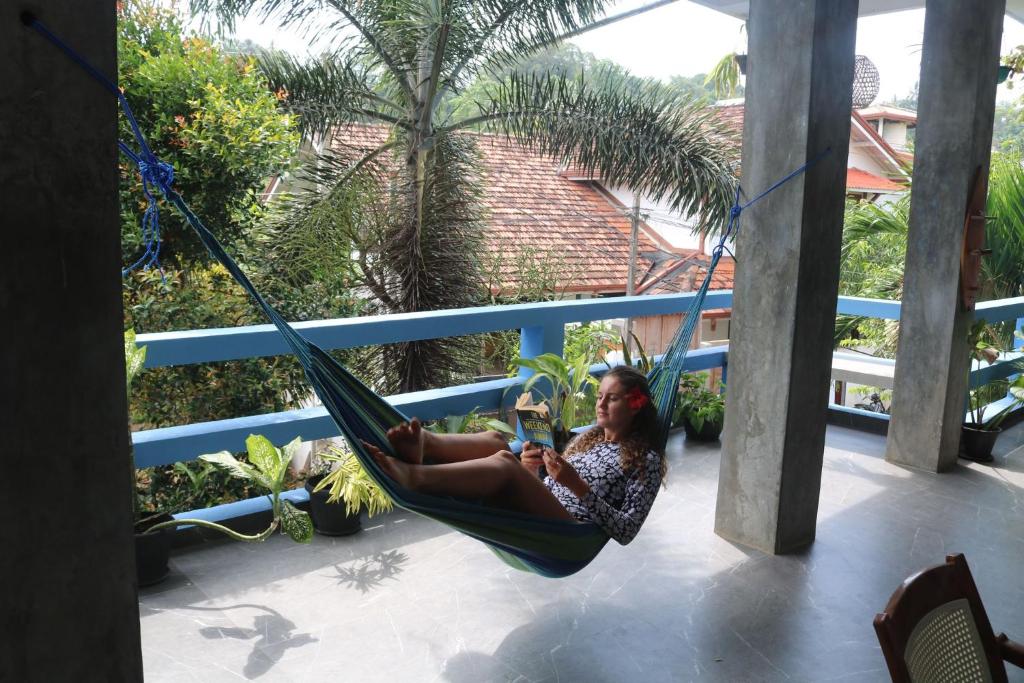 a woman sitting in a hammock on a porch at Costels Mirissa in Mirissa