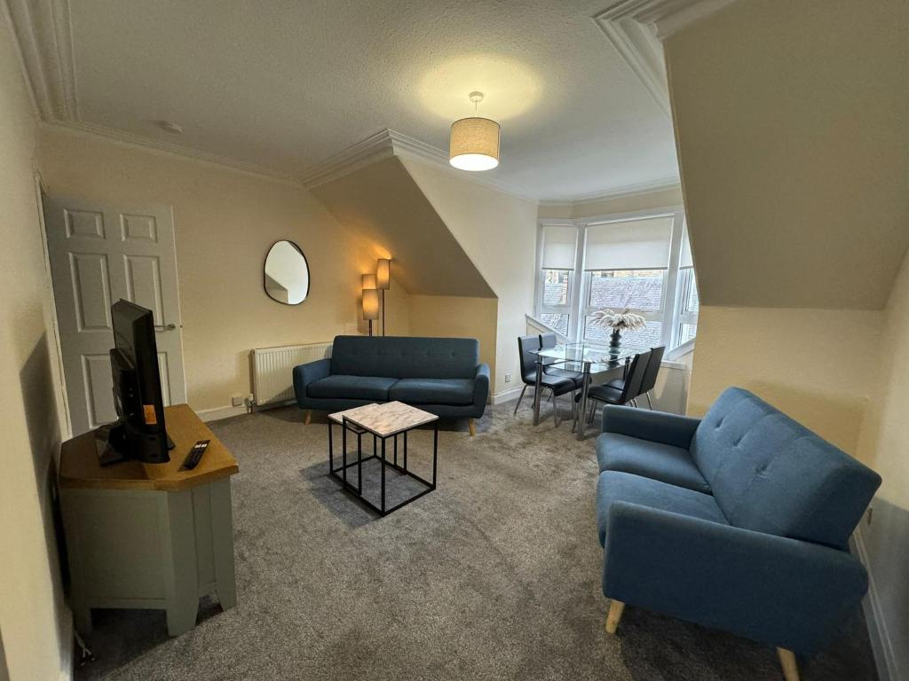 a living room with blue couches and a tv at Myreslaw Green Apartment, Hawick Scottish Borders in Hawick