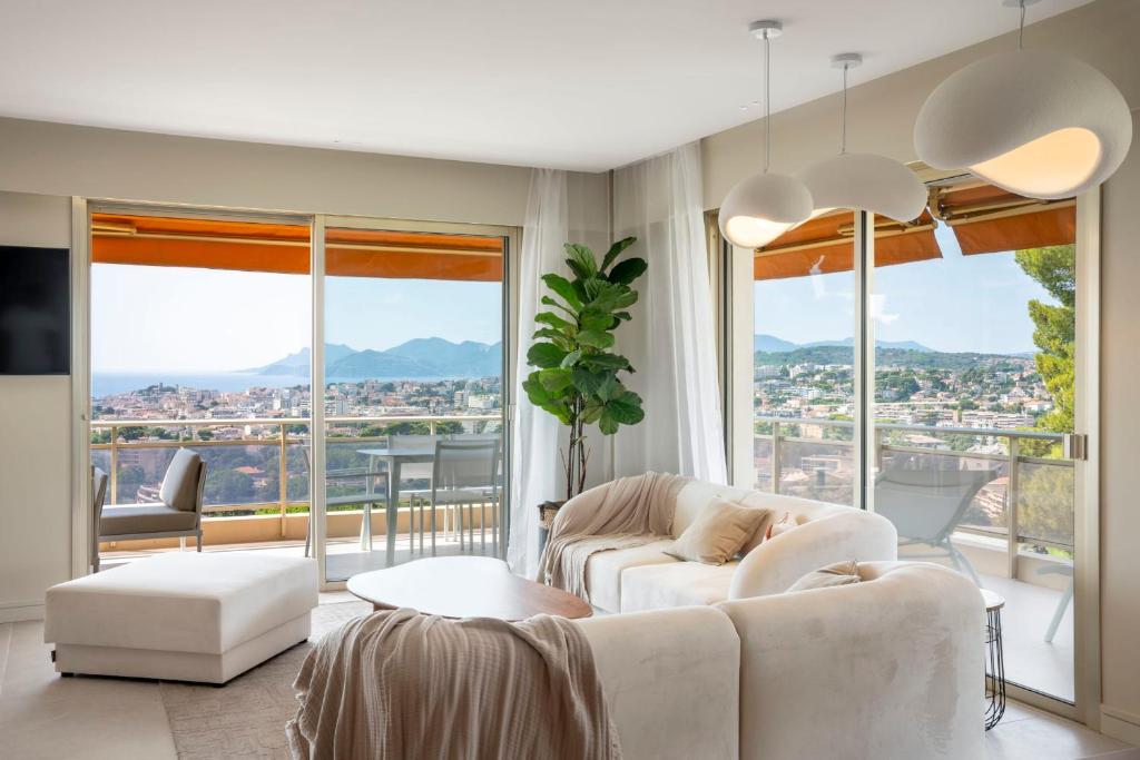 Elle comprend un salon doté d'un mobilier blanc et de grandes fenêtres. dans l'établissement REF 1965 - Le Cannet - Sea view apartment for rent, au Cannet