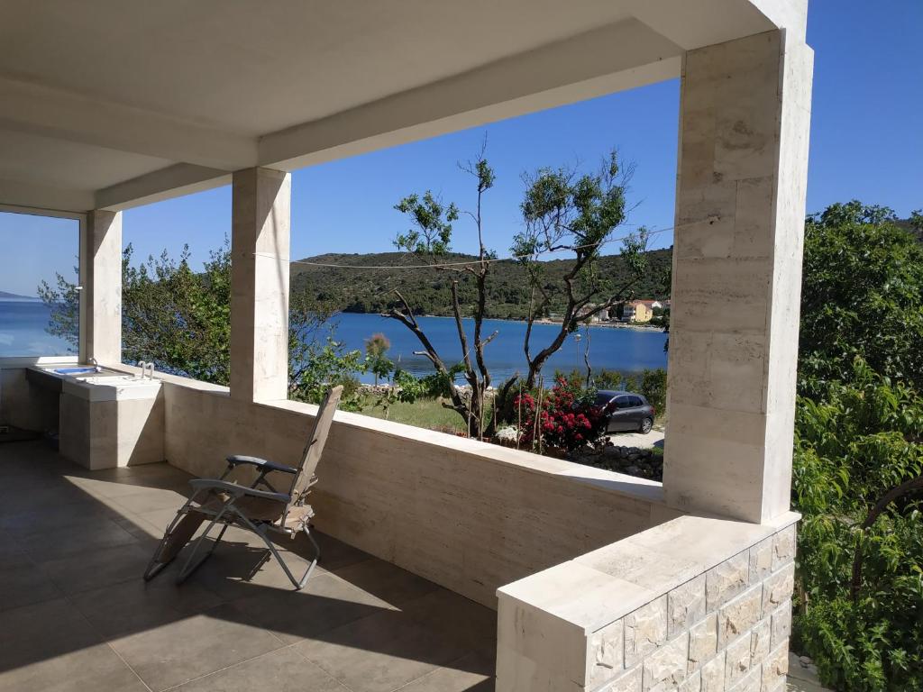 una silla sentada en un porche con vistas al océano en Holiday House Soline, en Veli Rat