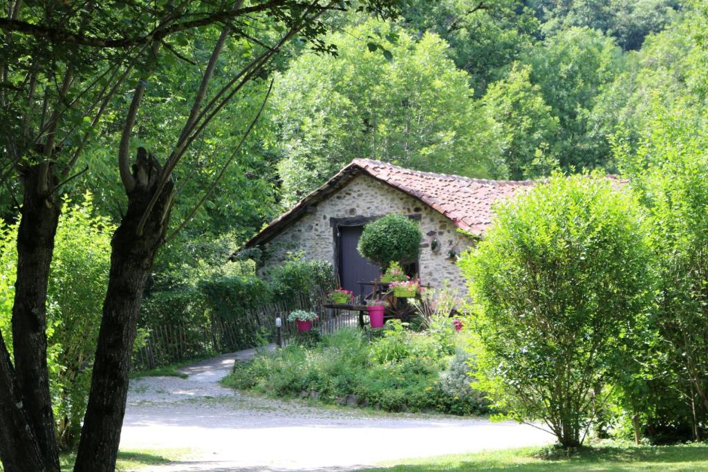 une petite maison en pierre au milieu d'un jardin dans l'établissement Camping Moulin De Chaules, à Saint-Constant