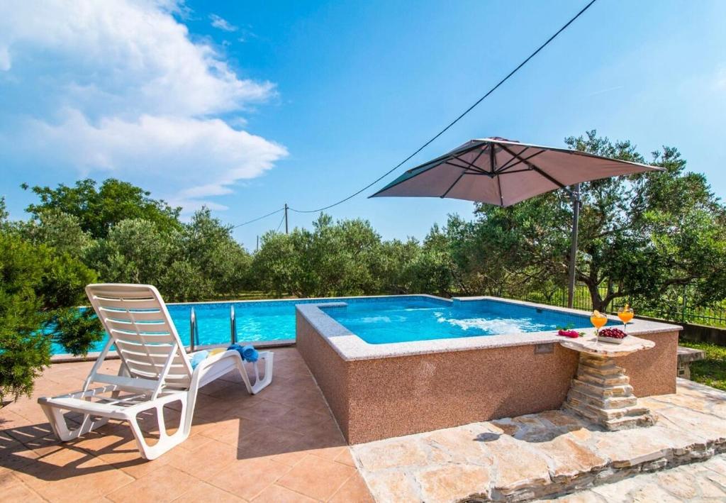 a chair and an umbrella next to a swimming pool at House Mare in Kastel Novi