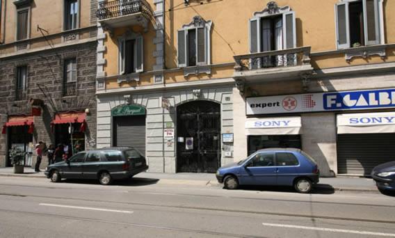 twee auto's geparkeerd aan de kant van een stadsstraat bij Hotel Eva in Milaan