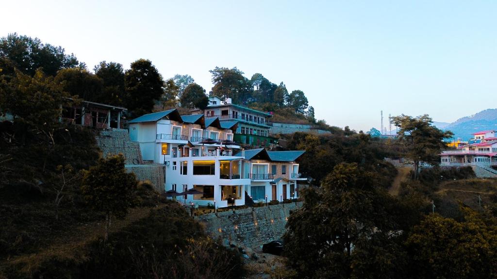un groupe de maisons sur une colline à côté d'un mur dans l'établissement The Barns Resort, à Bhimtal